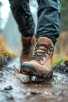A person steps through a muddy trail with sturdy hiking boots in a lush green forest photo