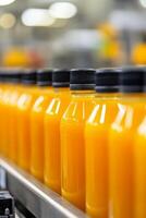 Bottles of fresh orange juice lined up on a conveyor belt in a factory setting photo