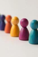Colorful wooden figures lined up on a white surface showcasing diverse shapes and hues photo