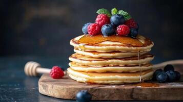 Delicious stack of fluffy pancakes topped with fresh berries and syrup on a wooden serving board photo