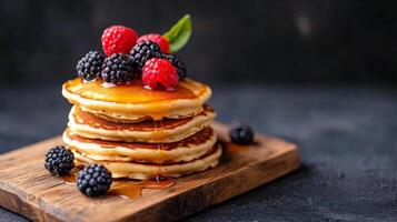 Delicious stack of fluffy pancakes topped with fresh berries and syrup on a wooden serving board photo