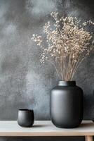 Black vases with dried flowers on a textured dark background in a minimalist style photo