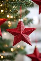 Red star ornament hanging from a Christmas tree decorated with lights and festive ornaments photo