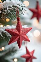 Red star ornament hanging from a Christmas tree decorated with lights and festive ornaments photo