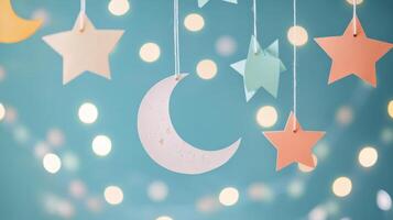 Decorated ceiling with paper stars and moon hanging against a teal backdrop with lights photo