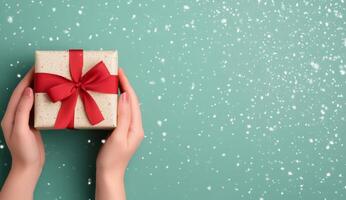 A person holding a beautifully wrapped gift in a snowy outdoor setting during winter festivities photo