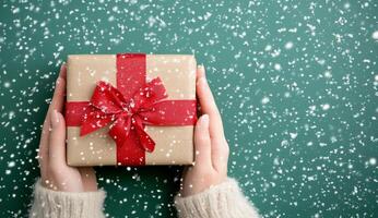 A person holding a beautifully wrapped gift in a snowy outdoor setting during winter festivities photo
