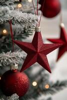 Red star ornament hanging from a Christmas tree decorated with lights and festive ornaments photo