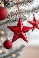 Red star ornament hanging from a Christmas tree decorated with lights and festive ornaments photo