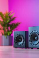 Two black speakers placed on a table with vibrant colored bokeh background at night photo