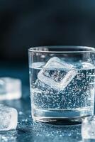 A refreshing glass of sparkling water with ice cubes on a dark background photo