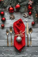 Festive holiday table setting with plaid napkin, silver cutlery, and pine cone decoration photo
