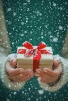 A person holds a beautifully wrapped gift with a red bow while snow falls gently around them photo