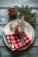 Festive holiday table setting with plaid napkin, silver cutlery, and pine cone decoration photo