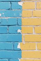 Colorful blue and yellow brick wall showing peeling paint and a faded urban texture photo