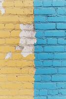 Colorful blue and yellow brick wall showing peeling paint and a faded urban texture photo