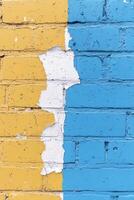 Colorful blue and yellow brick wall showing peeling paint and a faded urban texture photo