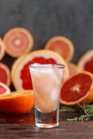 fresh grapefruits sliced and a tall glass filled with juice and vodka with ice photo