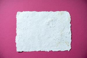 One Sheet of recycled paper on pink background. Secondary production. Making paper with your own hands at home. photo