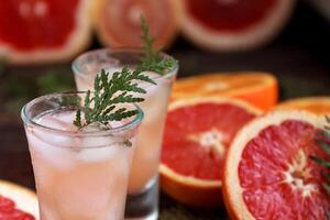 Drink glass with alcoholic cocktail with grapefruit and citrus, ice and juice on a wooden board, old rustic style photo