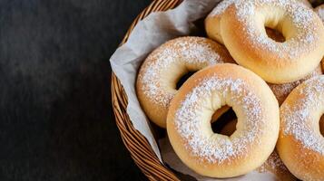 Freshly baked donuts dusted with powdered sugar in a wicker basket on a dark backdrop photo