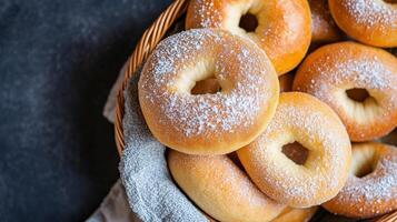 Freshly baked donuts dusted with powdered sugar in a wicker basket on a dark backdrop photo