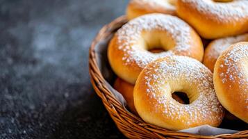 Freshly baked donuts dusted with powdered sugar in a wicker basket on a dark backdrop photo