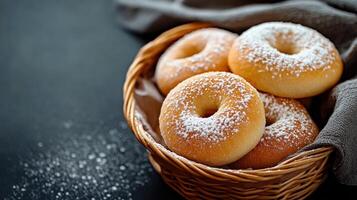 Freshly baked donuts dusted with powdered sugar in a wicker basket on a dark backdrop photo