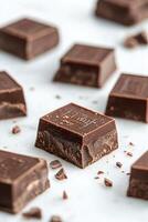 Delicious dark chocolate squares arranged on a marble surface with scattered crumbs photo