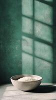 Soft shadows dance on a green wall with a bowl of rice and a plant on a wooden surface photo