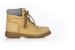 Single vintage durable yellow leather hiking boot with laces in a worn look. One beige used military shoe with thick sole. Isolated on white background. Studio light. Copy space photo