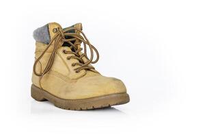 Single vintage durable yellow leather hiking boot with laces in a worn look. One beige used military shoe with thick sole. Isolated on white background. Studio light. Copy space photo