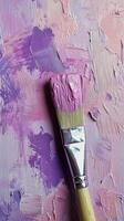 A close-up view of a paintbrush with vibrant purple paint on a textured pastel background photo