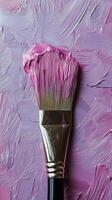 A close-up view of a paintbrush with vibrant purple paint on a textured pastel background photo