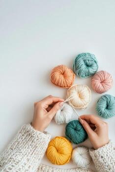 A person crafting with colorful yarn balls on a light background during a creative session photo