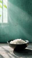 Soft shadows dance on a green wall with a bowl of rice and a plant on a wooden surface photo