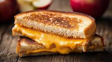 Grilled cheese sandwich with melted cheese served alongside fresh apples in a rustic setting photo