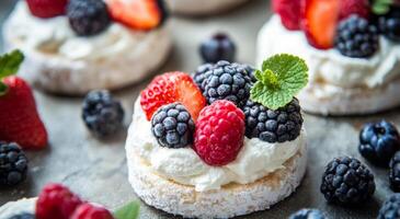 Fresh berries on a rice cake topped with cream and mint served on a gray background photo