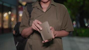 A close-up of an empty wallet in the hands of a middle-aged woman waiting alone at night, her financial struggles laid bare under the dim city lights. video