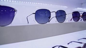 Sunglasses close-up on display, showcasing modern eyewear designs, diverse colors, stylish accessories in retail setting, neatly organized on shelves, highlighting fashionable choices. video