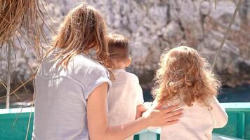 Mother with two small children stands on board ship. They look at mountain they are passing by. Concept of travel, vacation and happy family. video