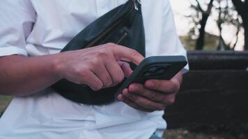 Businessman hands close up close-up communicating on his smartphone on a summer evening in the park video