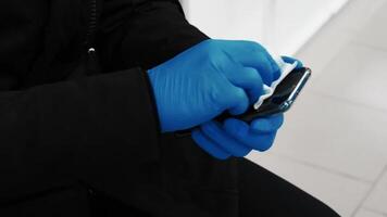 Concept of the COVID-19 coronavirus epidemic. A man with gloved hands wipes the screen of a mobile phone video