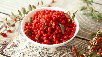fresh ripe red goji berries in a bowl on a wooden table video