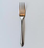 A shiny silver fork placed on a minimalist surface, highlighting its elegant design and shape photo