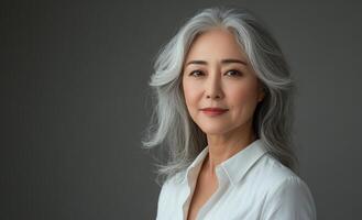 Elegant senior woman with silver hair poses confidently against a neutral background photo