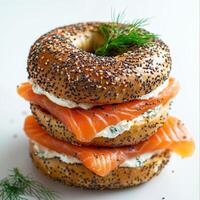 Layered bagel sandwich with smoked salmon and cream cheese topped with fresh dill photo