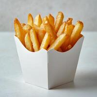 Crispy golden French fries served in a white takeout box on a light background photo