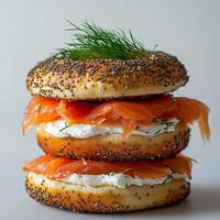 Layered bagel sandwich with smoked salmon and cream cheese topped with fresh dill photo