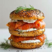Layered bagel sandwich with smoked salmon and cream cheese topped with fresh dill photo